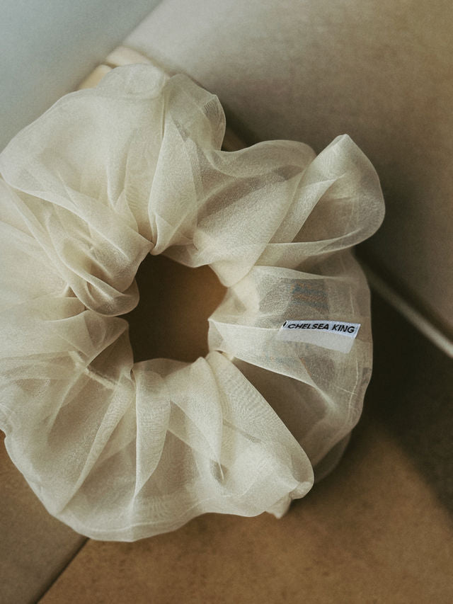 Beige scrunchie with a brand label on a neutral background